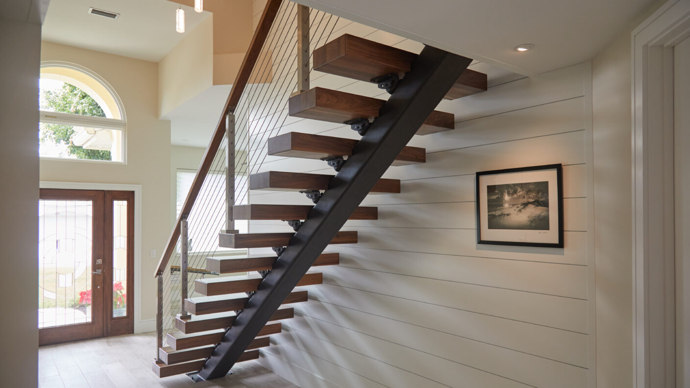 Floating stairs in an open foyer focusing on the steel stringer.