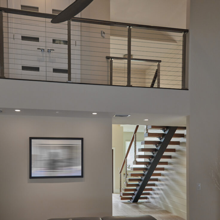 Wide shot of a floating staircase and balcony railing in an open concept home.