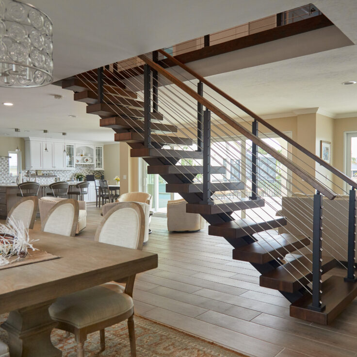 straight stairs in an open concept home feature white oak treads and rod railing.