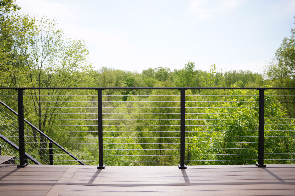 Express DIY cable railing on a contemporary deck looking out over a forest