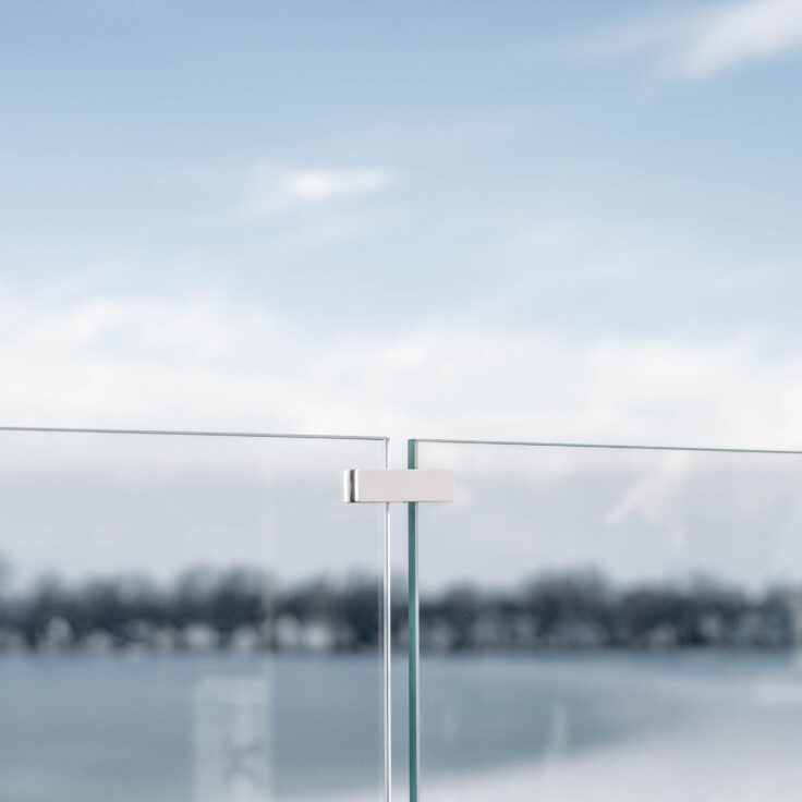 A White Glass Stabilizer Clip holds two glass railing panels together